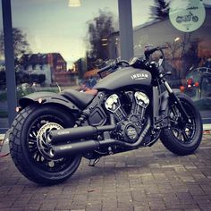 a black motorcycle parked in front of a building with large windows on the side of it