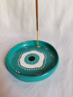 a blue bowl with an eye on it and a wooden stick sticking out of the top