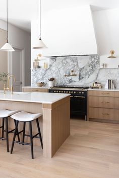 a kitchen with marble counter tops and stools next to an island in the middle