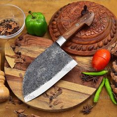 a large knife sitting on top of a wooden cutting board next to vegetables and spices