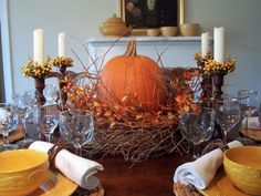 a dining room table set for thanksgiving with candles and pumpkins in the centerpiece