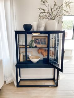 a black glass cabinet with pictures and vases on top