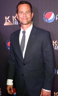 a man in a suit and tie standing on a red carpet