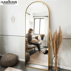 a woman sitting on a chair in front of a large mirror