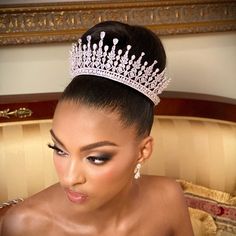 a woman wearing a tiara sitting on a couch with her hair in a bun