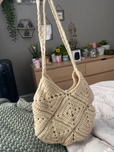 a crocheted bag hanging from a hook on a bed