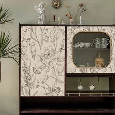 a cabinet with flowers on it next to a potted plant and vases in the corner