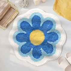 a blue and yellow flower rug sitting on top of a white table next to shoes