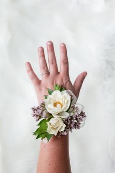 a person's hand with a flower wrist corsage on top of it