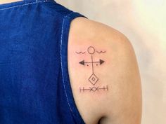 a woman's shoulder with an arrow and cross tattoo on her left side arm