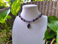 A witchy and whimsical bohemian glass choker necklace. Crafted with various shades of purple Czech glass beading, faceted black Czech glass beading, painted black wood beading, and a striking diamond-shaped black ceramic pendant at the center. *Handmade by me, one of a kind. *Hypoallergenic stainless steel chain and clasp.  Nickel Free. *Total Length: 14.5 inches *Length of Chain: 13 inches *Extender Length: 1 inch. If you require a longer extension chain to ensure a proper fit, please let me know!  Just let me know how long you would like your necklace under personalization instructions. (free of charge) *Width & Length of Ceramic Pendant: 11 mm x 20 mm *Clasp and Chain Material: Lobster claw and jump rings made of stainless steel.  *Strung on strong and flexible 23-strand stainless steel Purple Festival Jewelry With Black Beads, Mystical Purple Necklace For Festivals, Purple Beaded Necklace With Black Beads For Gift, Purple Beaded Choker Necklace, Purple Jewelry With Black Beads For Festival, Purple Necklace With Black Beads For Gift, Adjustable Purple Necklace With Black Beads, Gift Purple Necklace With Black Beads, Mystical Handmade Adjustable Beaded Necklace