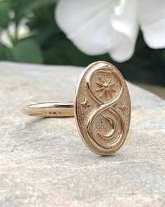 a gold ring sitting on top of a rock with flowers in the backgroun