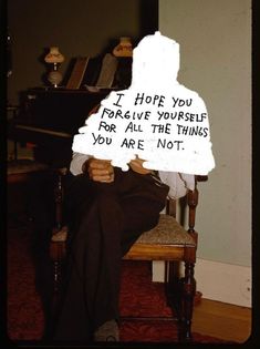 a person sitting in a chair with a sign on their head that says i hope you norve yourself for all the things you are not