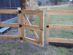 a wooden gate is open on the side of a farm house with a chicken coop in the background