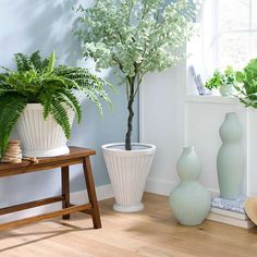 three vases with plants in them sitting on the floor next to a window sill