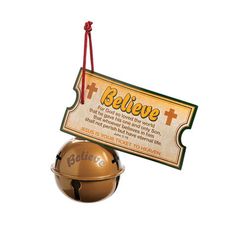 a golden bell with a sign that says believe and an orange ball hanging from it