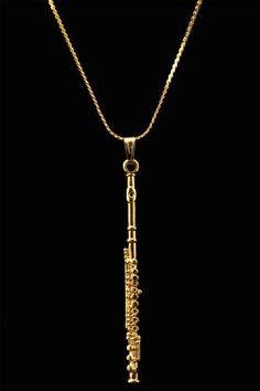 a gold necklace with an ornate design on the front and side, hanging from a chain