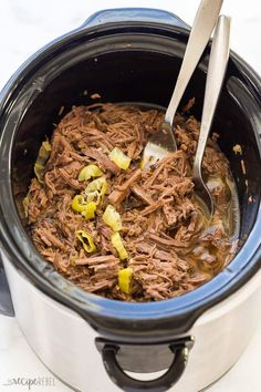 a slow cooker filled with shredded beef and vegetables, ready to be cooked in the crock pot