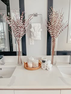 two vases filled with flowers sitting on top of a bathroom counter