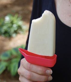 a woman holding a red and white popsicle