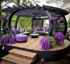 an outdoor living area with purple furniture and plants on the deck, surrounded by wooden steps