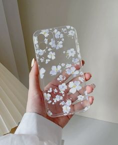 a person holding a clear case with white flowers on it