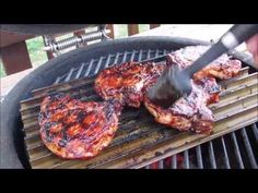 steaks being grilled on the grill with tongs