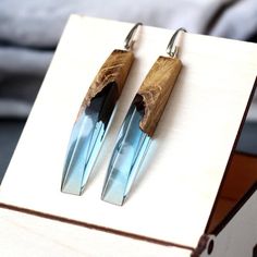 pair of earrings with wooden and glass details on hooks in wood box next to bed