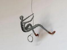 a wire sculpture hanging from the side of a wall next to a pair of scissors