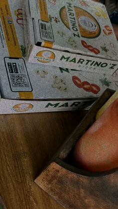 a wooden cutting board topped with two pieces of fruit next to boxes of maronies