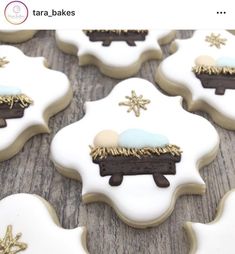 decorated cookies with frosting and gold decorations on a wooden table, including one in the shape of a nativity scene