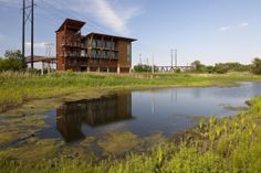 a large building sitting on the side of a river next to a lush green field