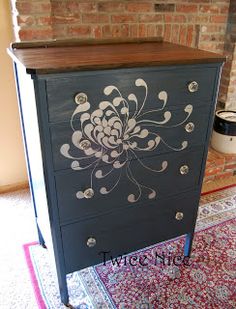 an ornate painted dresser in front of a brick wall with a rug on the floor