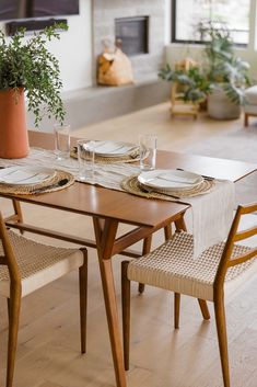 a dining room table set for four with place settings and plates on it, in front of a fireplace