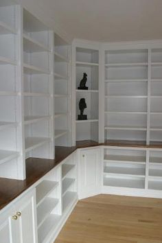 an empty room with white bookcases and wooden floors