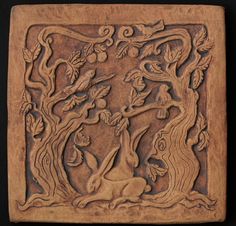 a carved wooden plaque with an animal and tree