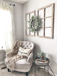 a living room with a chair, window and wreath on the wall