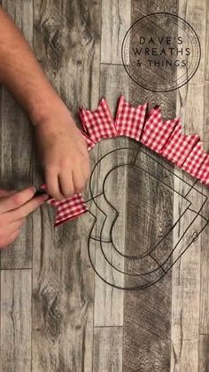 someone is cutting out some red and white checkered ribbon on the wood floor with scissors