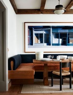 a dining room table with two chairs and a bench in front of a painting on the wall