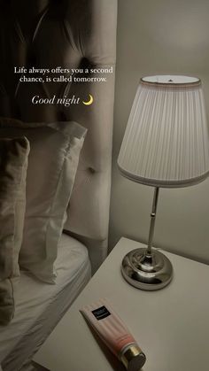 a lamp on a night stand next to a bed with pillows and a pillow in the corner