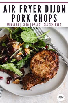 a white plate topped with meat and salad next to a fork on top of a table