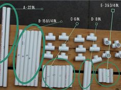 several white pipes and fittings laid out on a wooden table with green wires connected to them