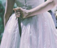 a woman in a pink dress holding onto a black tie and wearing a white dress