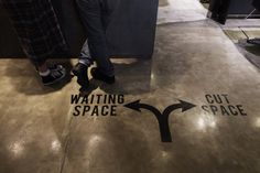 two people standing in front of a sign that says waiting space and cut space on the floor