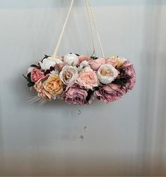 a flower arrangement hanging on the wall in a room with white and pink flowers around it