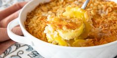 a close up of food in a bowl on a table with a person holding a spoon