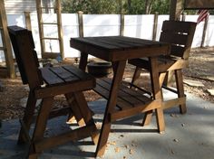 two wooden chairs sitting next to each other on a patio near a table and chair