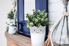 a potted plant sitting on top of a wooden table next to a mirror and vase