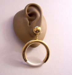 White Lucite accent jumbo size hoops pierced post stud earrings vintage gold tone smooth polished reflective metal finish extra large round domed top button open dangle rings. In excellent vintage aged never worn vintage condition. Measures 2 1/2 inches long 1 5/8 inches wide hoop. Retro White Dangle Jewelry, Retro White Round Jewelry, Retro Round Pierced Jewelry, Nickel-free White Round Plug Earrings, Nickel-free Round White Plug Earrings, Nickel Free White Round Plug Earrings, Dangle Rings, Reflective Metal, Dangle Ring