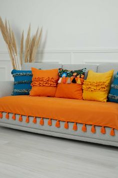 a couch with orange and blue pillows on it